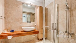 Une salle de bain moderne avec un grand miroir, un lavabo sur colonne et une douche à parois de verre.