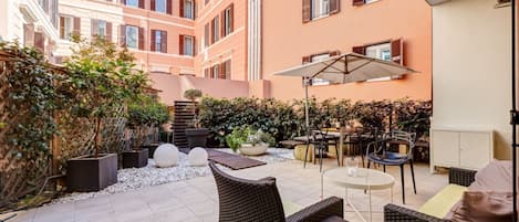 A courtyard with outdoor seating, potted plants, and a building with multiple windows.