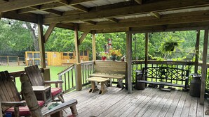 A wooden deck with a bench and chairs, surrounded by a wooden fence and greenery. - Rustic getaway on 3 acres - Only minutes from TEXS A&M University.  (Bryan)