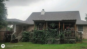 A brick house with a covered porch, a chimney, and a small garden area with potted plants. - Rustic getaway on 3 acres - Only minutes from TEXS A&M University.  (Bryan)