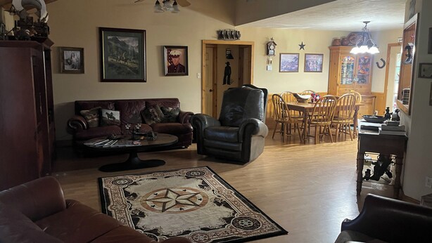 A spacious living room with a leather sofa, a coffee table, and a dining area with wooden chairs and a table. - Rustic getaway on 3 acres - Only minutes from TEXS A&M University.  (Bryan)