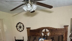 A bedroom with a wooden bed, a ceiling fan, a wall clock, and a small table with a chair. - Rustic getaway on 3 acres - Only minutes from TEXS A&M University.  (Bryan)