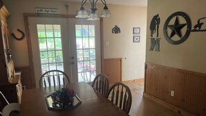 A dining area with a wooden table and chairs, a chandelier, and a view through glass doors to an outdoor patio. - Rustic getaway on 3 acres - Only minutes from TEXS A&M University.  (Bryan)
