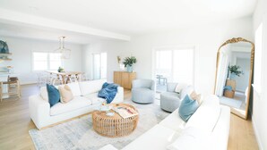 Un salón amplio con un sofá blanco, una mesa redonda de centro y un comedor con mesa y sillas de madera.