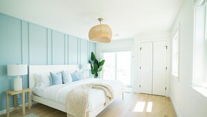 Un dormitorio con cama, mesita de noche, lámpara y una lámpara colgante.