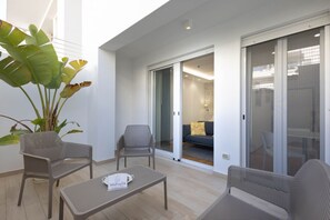 Un balcon agrémenté de meubles en osier, d’une plante en pot et d’une porte-fenêtre coulissante donnant sur un espace de vie.