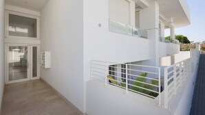 A modern two-story building with a balcony, a glass door entrance, and a white exterior. - WePuglia – Appartamento Grottelle (Polignano a Mare)