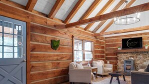 A log cabin interior with wooden walls, a stone fireplace, and a cozy seating area. - Cabin in the Trees, Hot Tub, Fire Pit (Rockbridge)