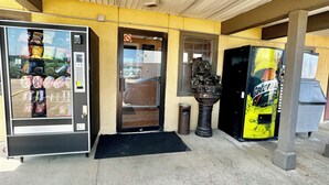 A vending machine, a door, and a trash can outside a building. - Seagoville Inn (Seagoville)