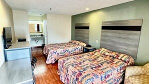 A hotel room with two beds, a desk, and a chair. - Seagoville Inn (Seagoville)