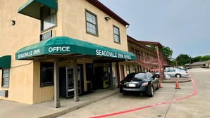 A Seagoville Inn office building with a green awning, a parking lot, and a few cars parked nearby. - Seagoville Inn (Seagoville)
