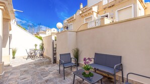 A courtyard with a sofa, chairs, and a table, surrounded by a low wall and potted plants. - 2 bedroom stunning apartment in Torrevieja (Torrevieja)