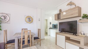 A modern kitchen with a built-in TV, wooden cabinets, and a dining area with a table and chairs. - 2 bedroom stunning apartment in Torrevieja (Torrevieja)