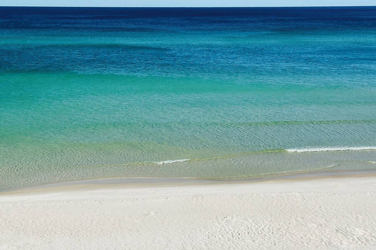 A beach with clear turquoise water and a sandy shore.