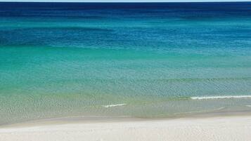 Praia particular, areia branca, espreguiçadeiras, guarda-sóis