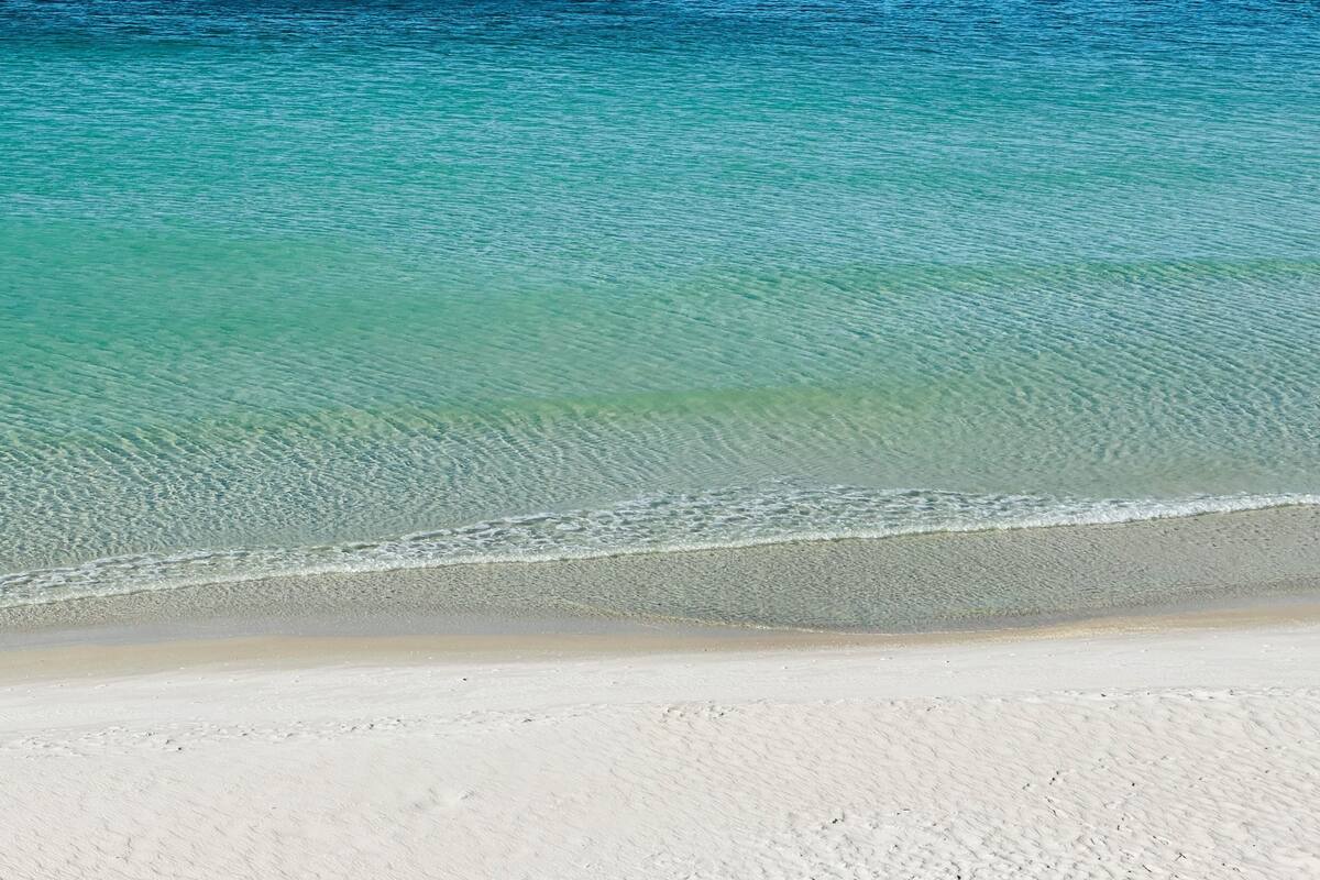 A beach with clear turquoise water and white sand.