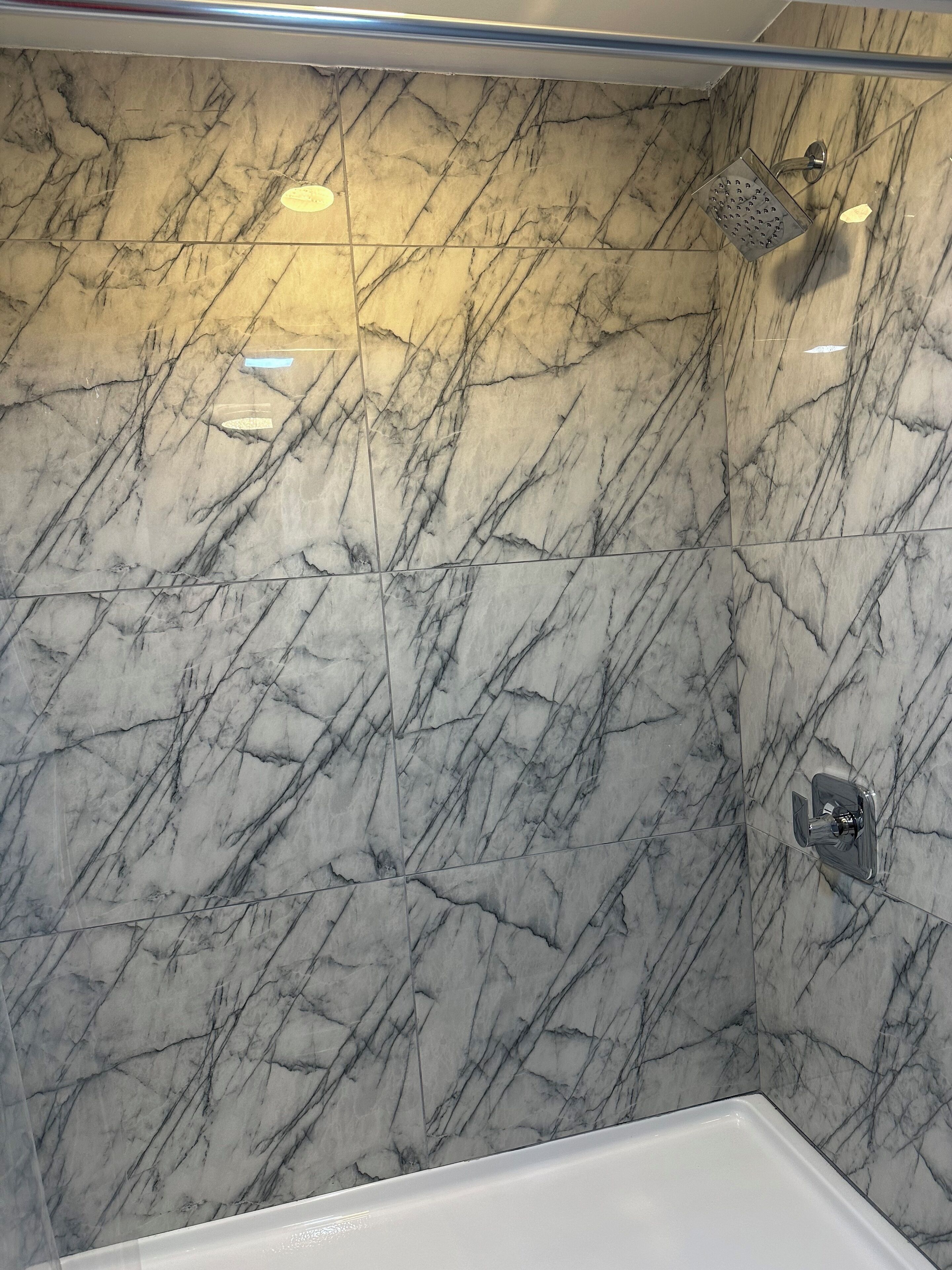 Un baño con paredes de mármol y una ducha.