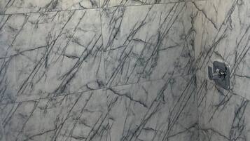 Un baño con paredes de mármol y una ducha.