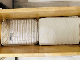 A wooden bench with a striped cushion and a plain white cushion.