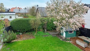 A residential backyard with a green lawn, a wooden deck, a small shed, and flowering trees. - Awesome home in Limhamn with kitchen (Limhamn)