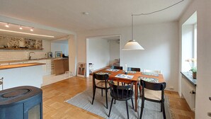 A compact kitchen with a dining area featuring a wooden table and chairs, a hanging light fixture, and a view through an open doorway. - Awesome home in Limhamn with kitchen (Limhamn)