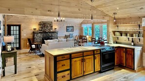 A spacious kitchen with wooden cabinets, a central island, and a stone fireplace.