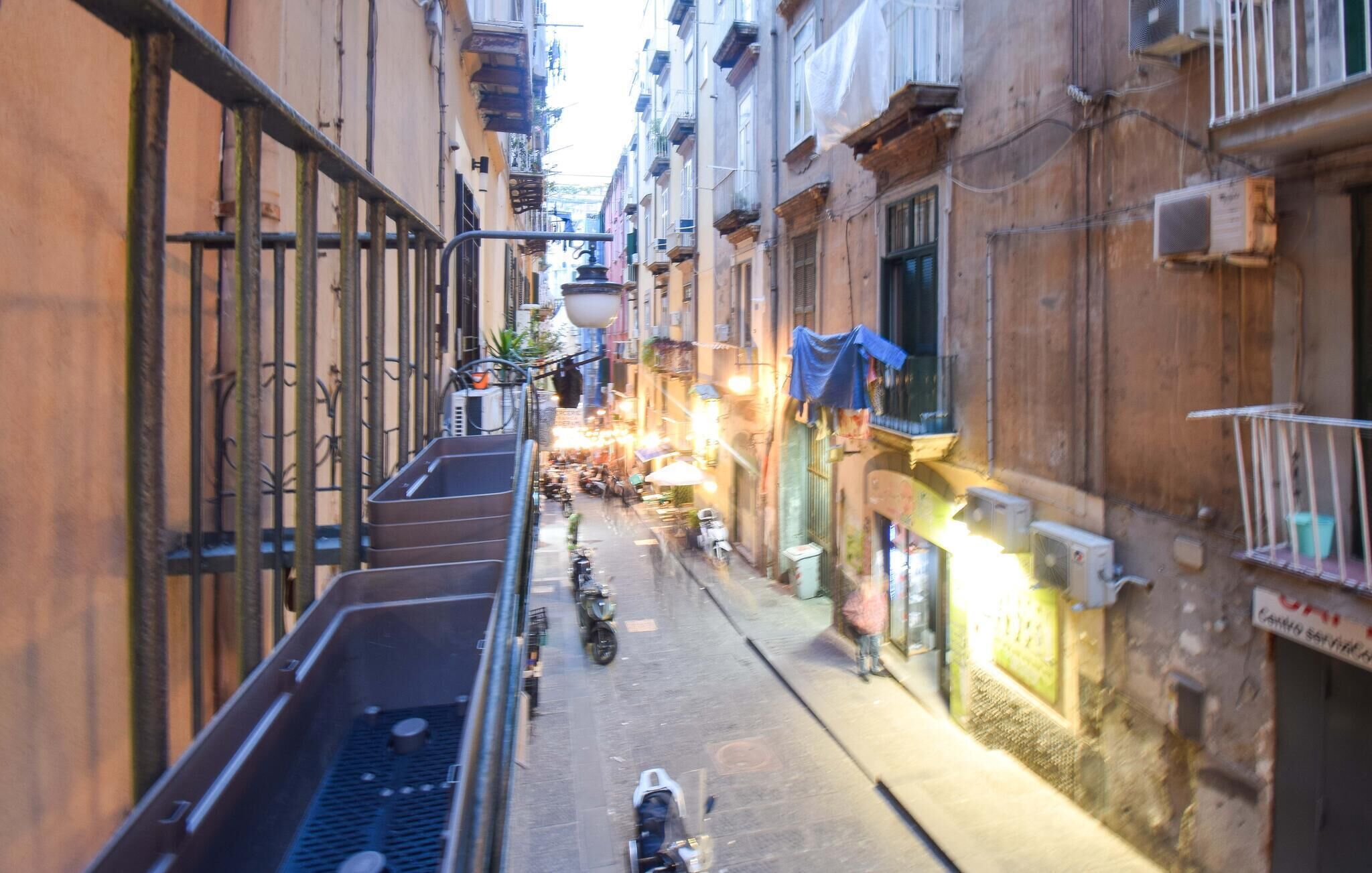 Una calle estrecha flanqueada por edificios, algunos con balcones y terrazas.