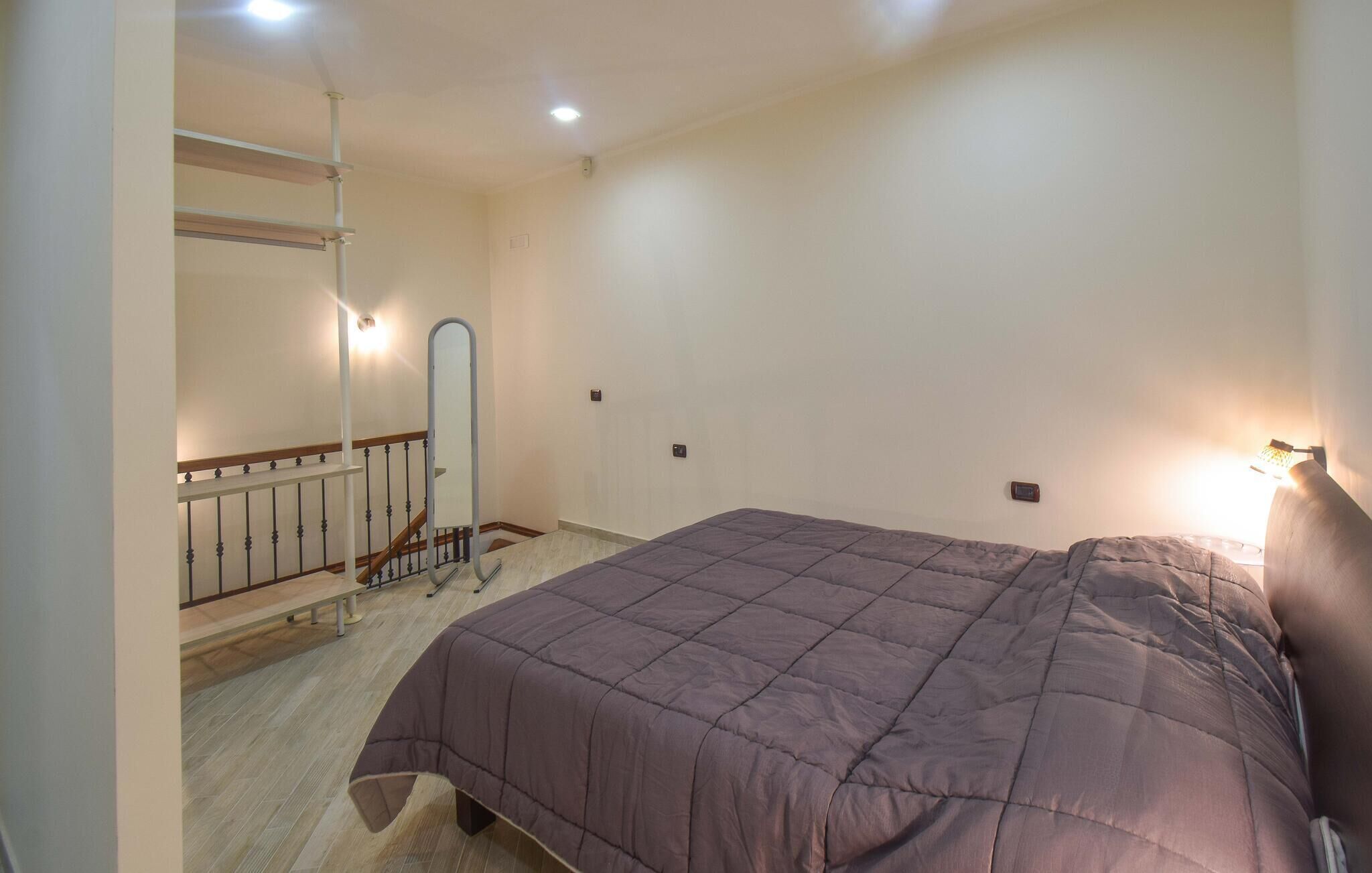 Quarto com cama, espelho, mesa pequena e escada.