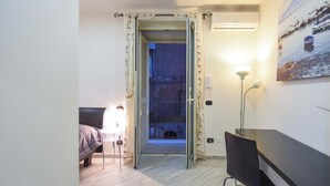 Ein Hotelzimmer mit Bett, Schreibtisch, Stuhl, Schreibtischlampe und Blick ins Freie.