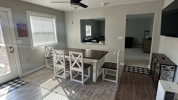 A dining area with a table and chairs, a ceiling fan, a window with blinds, and a door. - Little Sac Lake House w Starlink internet (Greenfield)