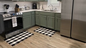 A kitchen with green cabinets, a stainless steel refrigerator, a microwave, a stove, and a sink. - Little Sac Lake House w Starlink internet (Greenfield)