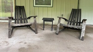 Two wooden Adirondack chairs and a small table in front of a green building with a window and a door. - Little Sac Lake House w Starlink internet (Greenfield)
