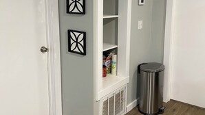 A hallway with a white door, a white built-in shelf unit, a trash can, and three black wall art pieces. - Little Sac Lake House w Starlink internet (Greenfield)