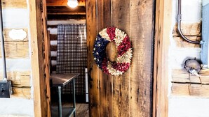 A wooden door with a wreath, a metal bench, and a wooden floor.