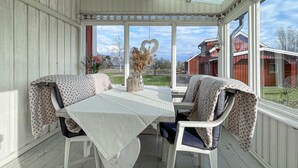 A covered porch with a table and chairs, a heart-shaped decoration, and a view of red buildings in the background.