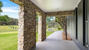A stone archway leading to a covered outdoor area with a view of a landscaped garden and a pathway. - Berry Beach Farm (Berry)