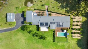 An aerial view of a modern house with a large deck, a swimming pool, and a well-maintained lawn. - Berry Beach Farm (Berry)