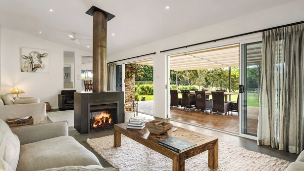 A modern living room with a fireplace, comfortable seating, and a view of the outdoors. - Berry Beach Farm (Berry)