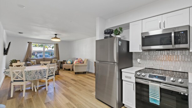 A modern kitchen with stainless steel appliances, a dining area with a table and chairs, and a view of the outdoors through a window. - Gorgeous relaxing 2BD Near Ft. Myers Beach (Fort Myers)