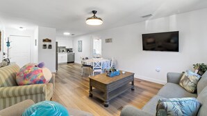 A living room with a sofa, armchair, and a coffee table. There is a television mounted on the wall and a ceiling light fixture. - Gorgeous relaxing 2BD Near Ft. Myers Beach (Fort Myers)