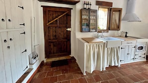 Uma cozinha rústica com porta de madeira, pia, armários e janela.