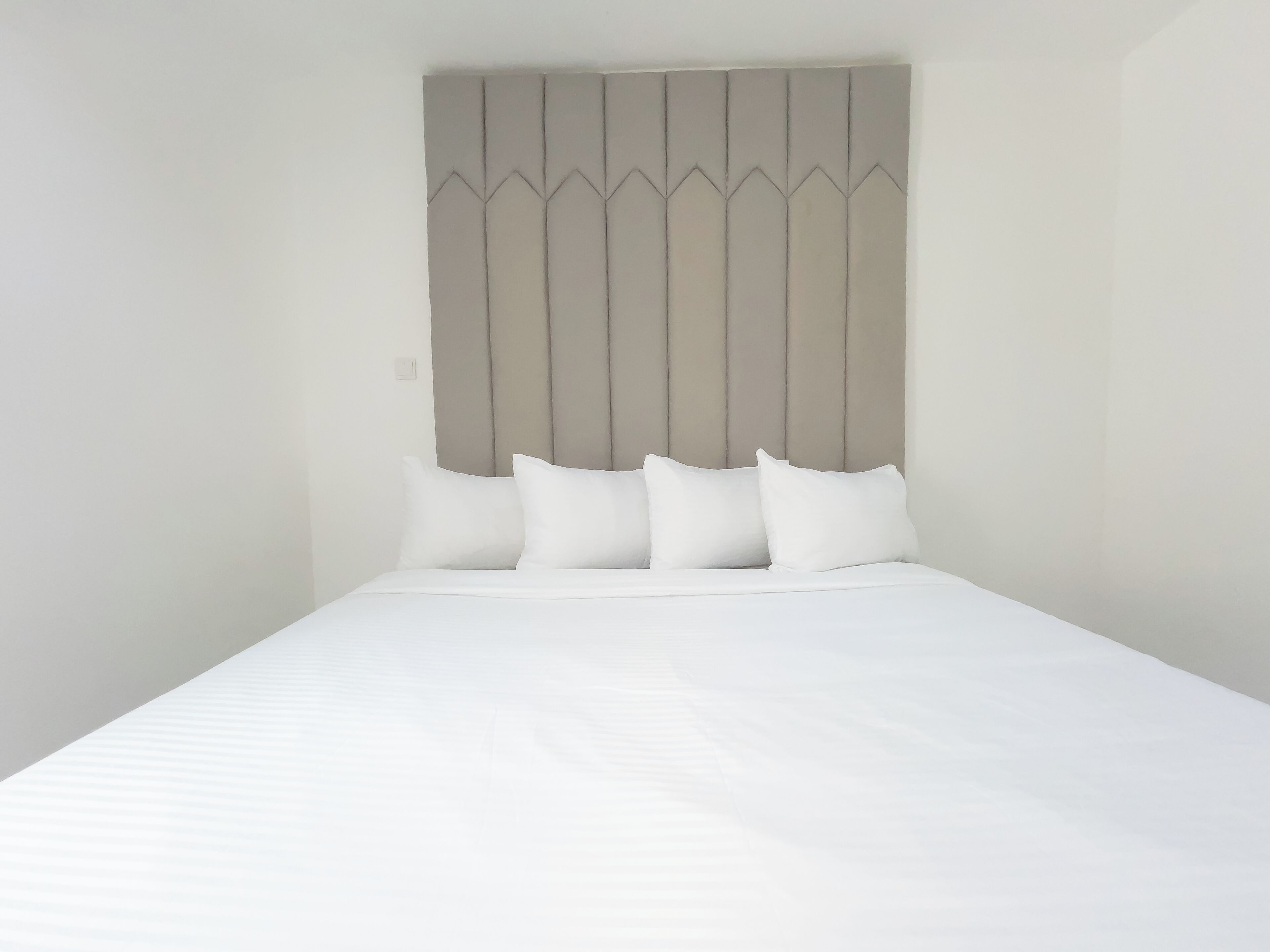 A neatly made bed with a headboard featuring a geometric pattern.
