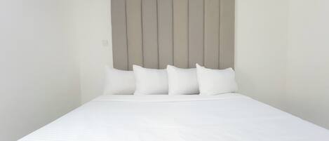 A neatly made bed with a headboard featuring a geometric pattern.