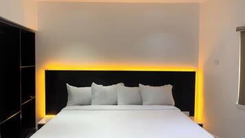 Una habitación de hotel moderna con una cama grande, un cabecero negro y una mesita de noche.