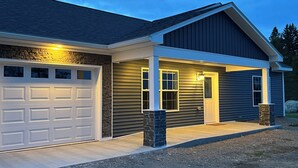A two-story house with a garage, a covered porch, and stone pillars.