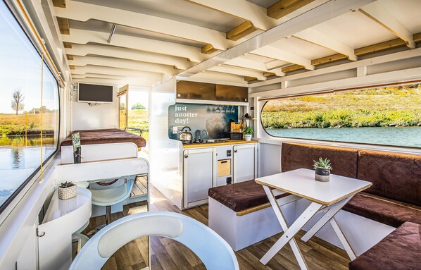 A compact RV interior with a kitchenette, a dining area, and a sleeping space. - Cozy ship in Ophoven with lake view (Ophoven)