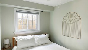 A bedroom with a bed, a window, a ceiling fan, and a wall-mounted light fixture. - Little Bell's Bungalow / Walkable to Saugatuck and Douglas / Updated (Saugatuck)