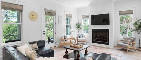 A modern living room with a black leather sofa, a wooden coffee table, and a fireplace.