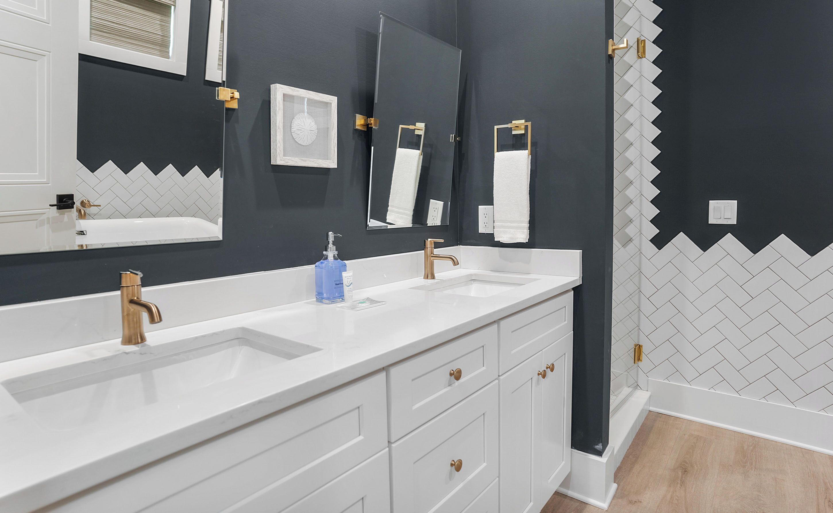 Une salle de bain moderne avec deux lavabos, un grand miroir et un porte-serviettes.