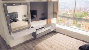 A modern bedroom with a large bed, a TV mounted on the wall, and a city view through the window.